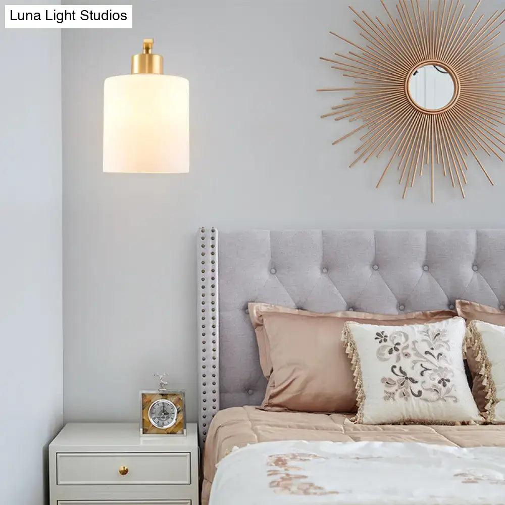 Modern brass cylinder wall sconce with milk glass shade bedroom light