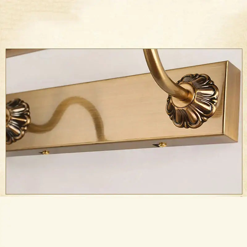 Ornate brass bathroom mirror lamp with decorative scrollwork