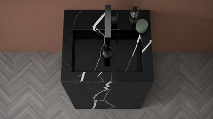 Black marble sink with faucet on a gray and brown patterned floor