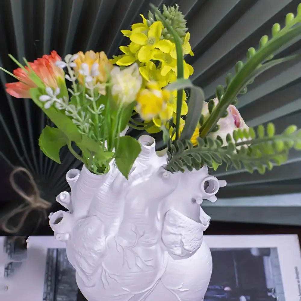 White anatomical heart vase with colorful flowers for living room