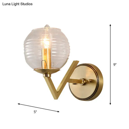 Brass ball sconce with ribbed glass shade for bedroom wall lighting