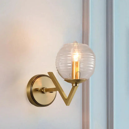 Brass ball sconce with ribbed glass shade for bedroom wall lighting
