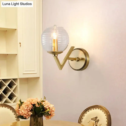 Brass ball sconce with ribbed glass shade for bedroom wall lighting