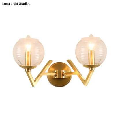 Brass ball sconce with ribbed glass shade for bedroom wall lighting