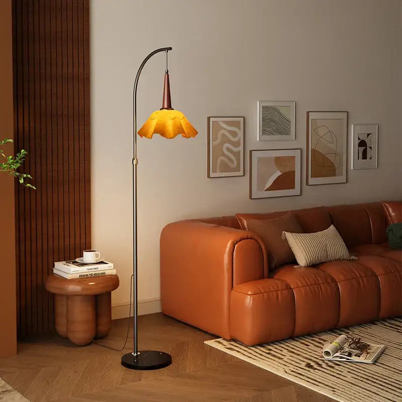 Curved black floor lamp with amber petal shade and living room shelf