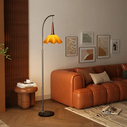Curved black floor lamp with amber petal shade and living room shelf