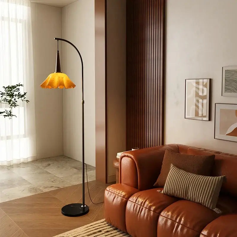 Curved black floor lamp with amber petal shade and living room shelf