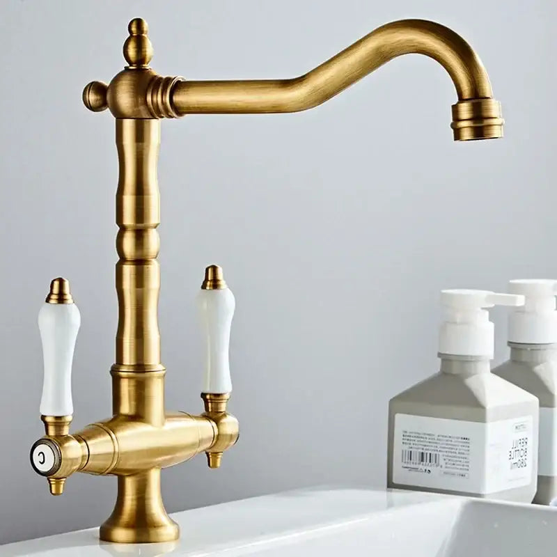 Antique brass kitchen faucet with ceramic handles and curved spout