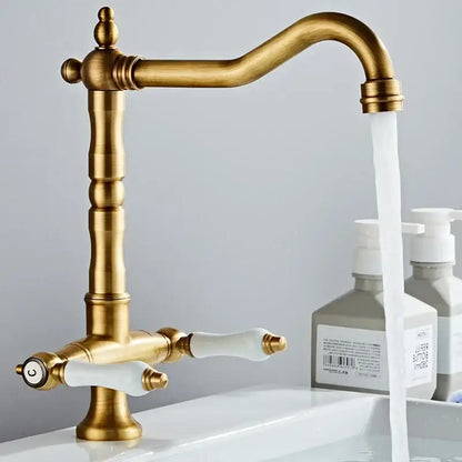 Antique brass kitchen faucet with ceramic handles and curved spout
