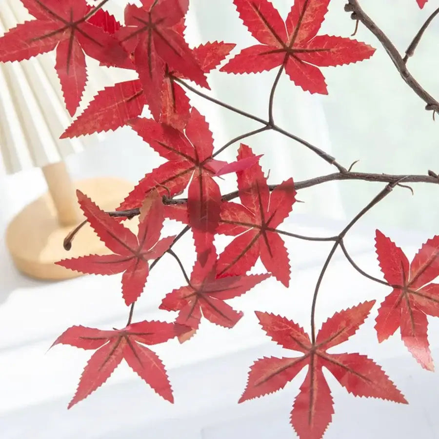 Vibrant red artificial maple leaf bouquet in white vase living room