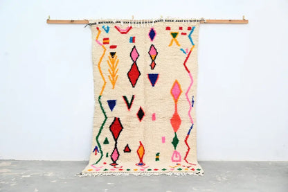 Handmade beige azilal rug with colorful geometric patterns bedroom