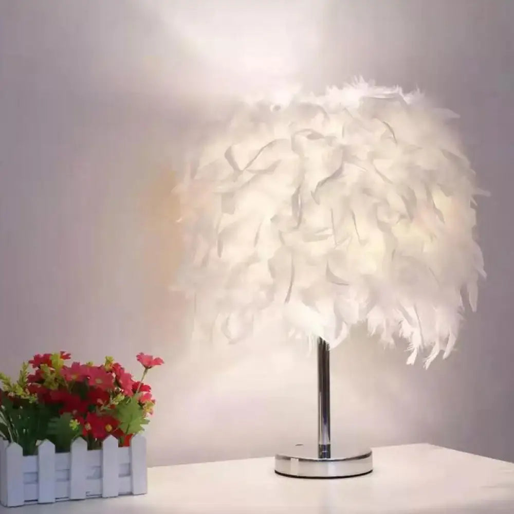 Modern chrome table light with white feather shade for bedroom