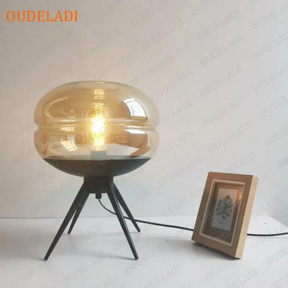 Modern amber glass table lamp with black tripod base for bedroom decor