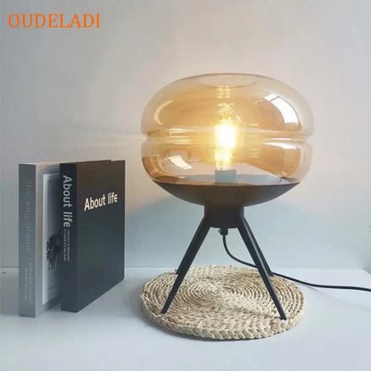 Modern amber glass table lamp with black tripod base for bedroom decor