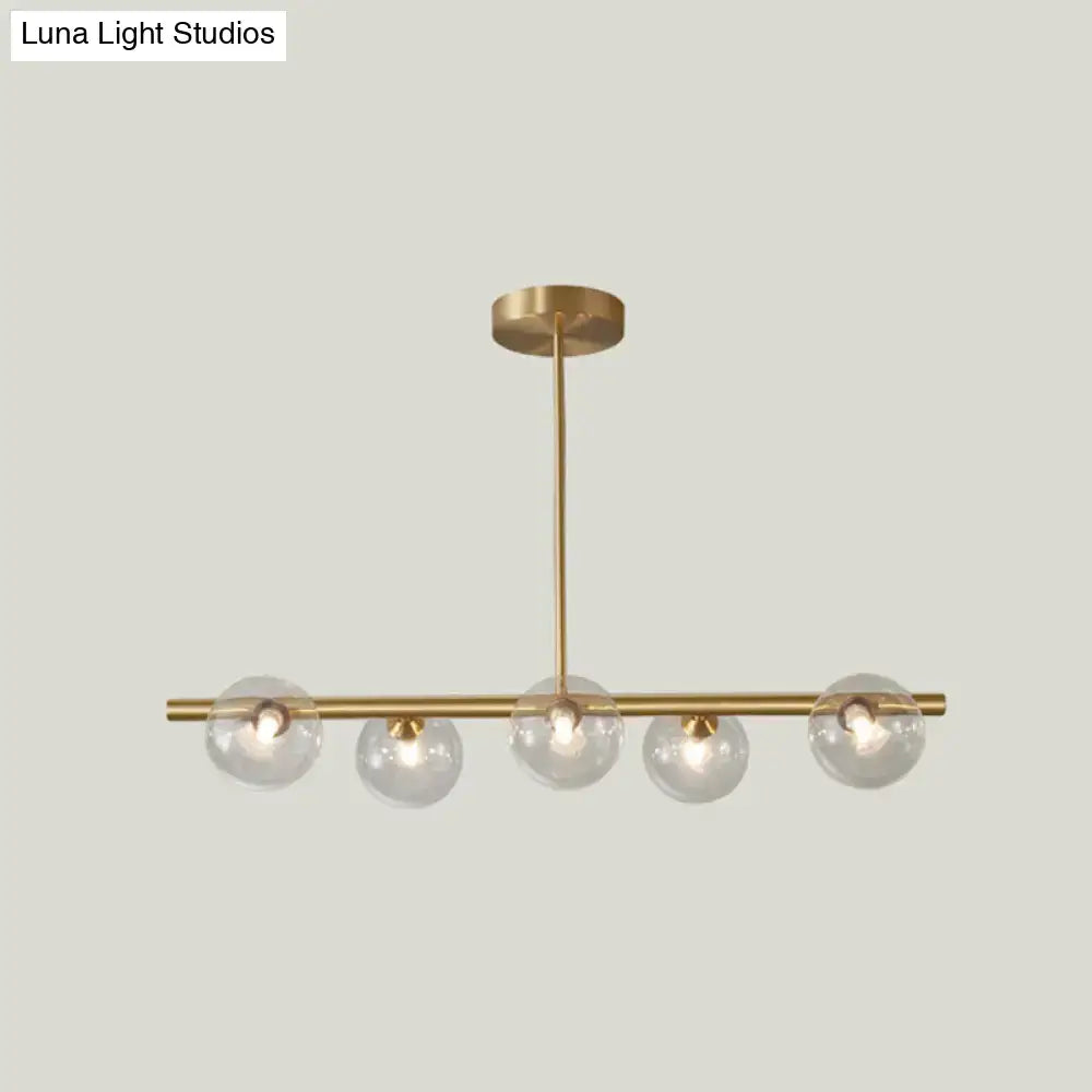 Modern brass 5-light pendant light with spherical glass shade dining room