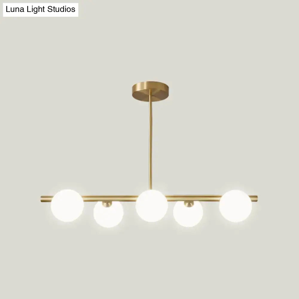 Modern brass 5-light pendant light with spherical glass shade dining room