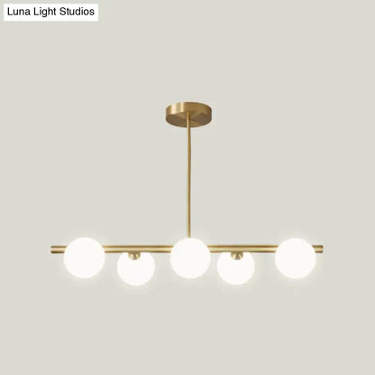 Modern brass 5-light pendant light with spherical glass shade dining room