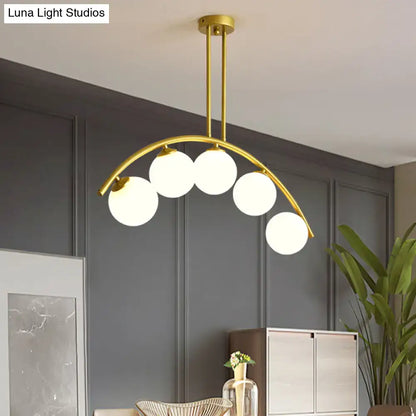 Modern brass arch arm 5-light pendant – dining room glass orb light
