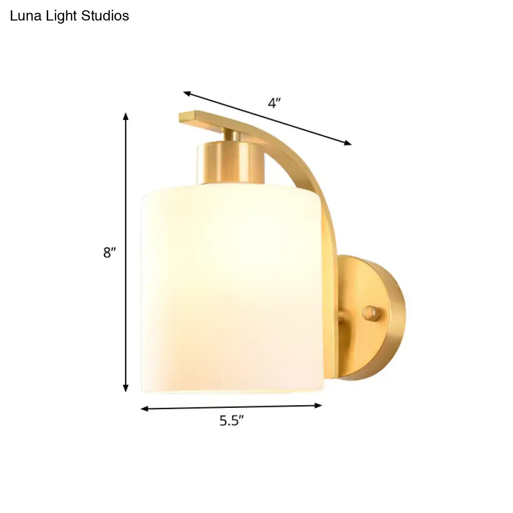 Modern brass cylinder wall sconce with milk glass shade bedroom light