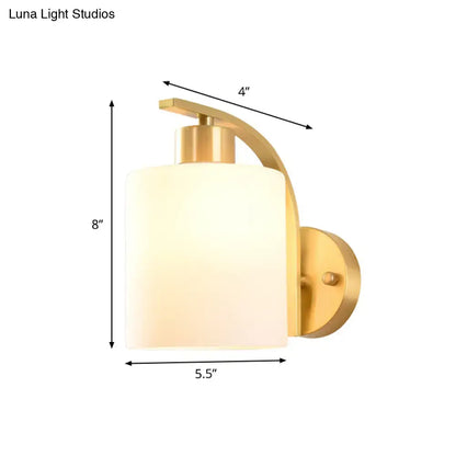 Modern brass cylinder wall sconce with milk glass shade bedroom light