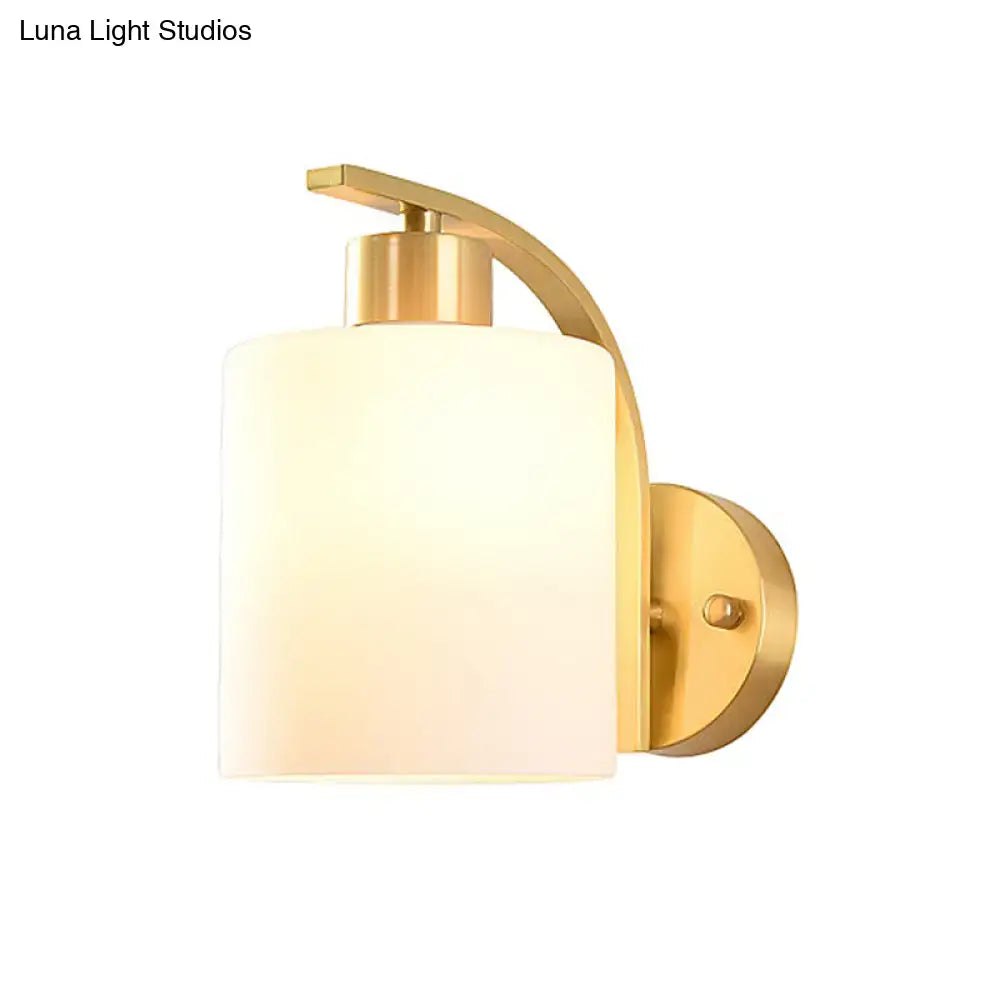 Modern brass cylinder wall sconce with milk glass shade bedroom light