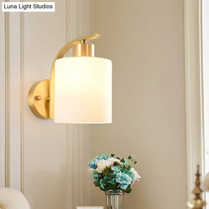 Modern brass cylinder wall sconce with milk glass shade bedroom light