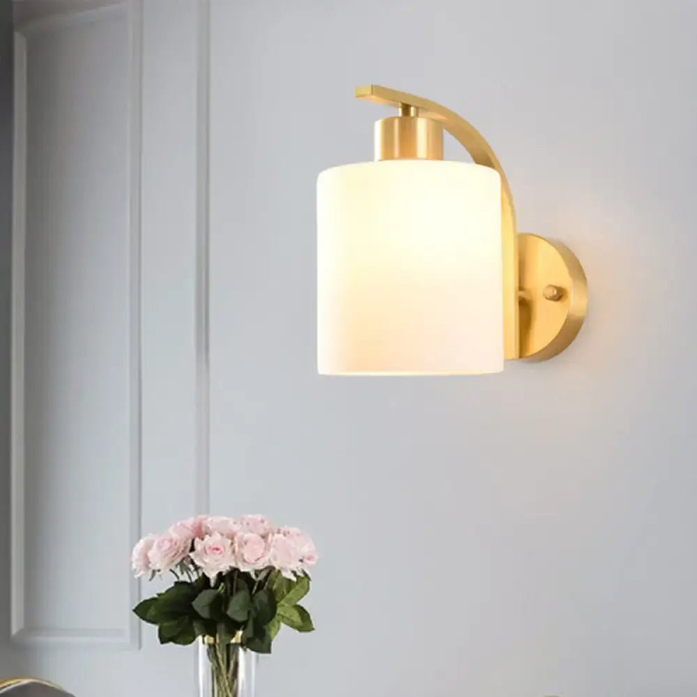 Modern brass cylinder wall sconce with milk glass shade bedroom light
