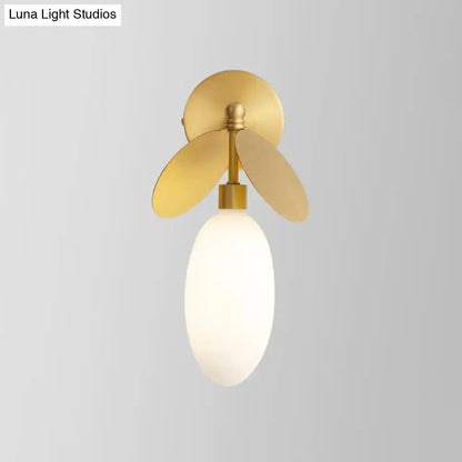 Modern brass leaf wall lamp with cream glass bedroom sconce
