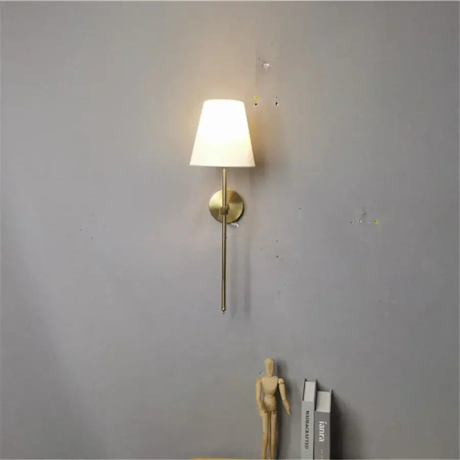 Modern brass led wall sconce with white fabric shade for bedroom