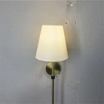 Modern brass led wall sconce with white fabric shade for bedroom