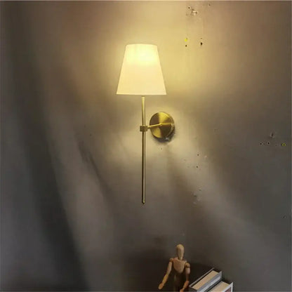 Modern brass led wall sconce with white fabric shade for bedroom