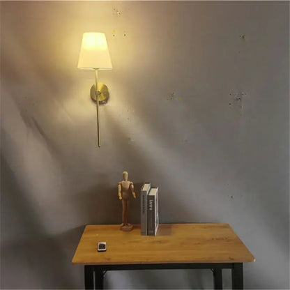 Modern brass led wall sconce with white fabric shade for bedroom
