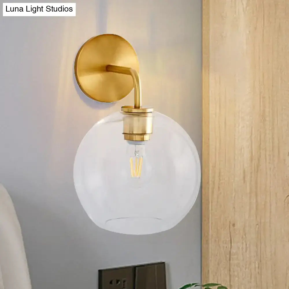 Modern brass wall lamp with clear white glass globe – bedroom