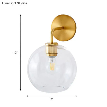 Modern brass wall lamp with clear white glass globe – bedroom