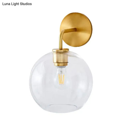 Modern brass wall lamp with clear white glass globe – bedroom