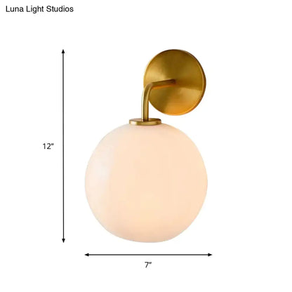 Modern brass wall lamp with clear white glass globe – bedroom