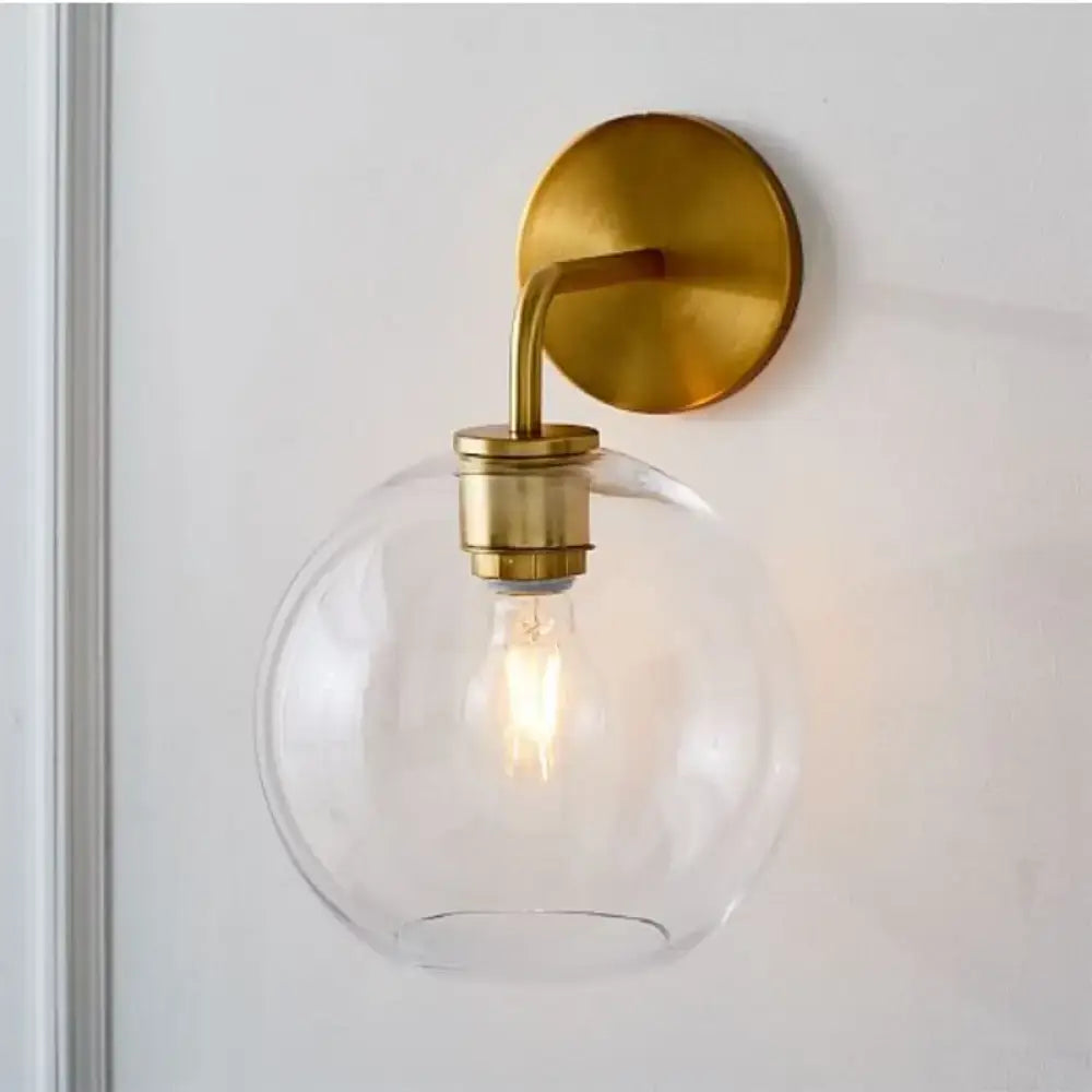 Modern brass wall lamp with clear white glass globe – bedroom