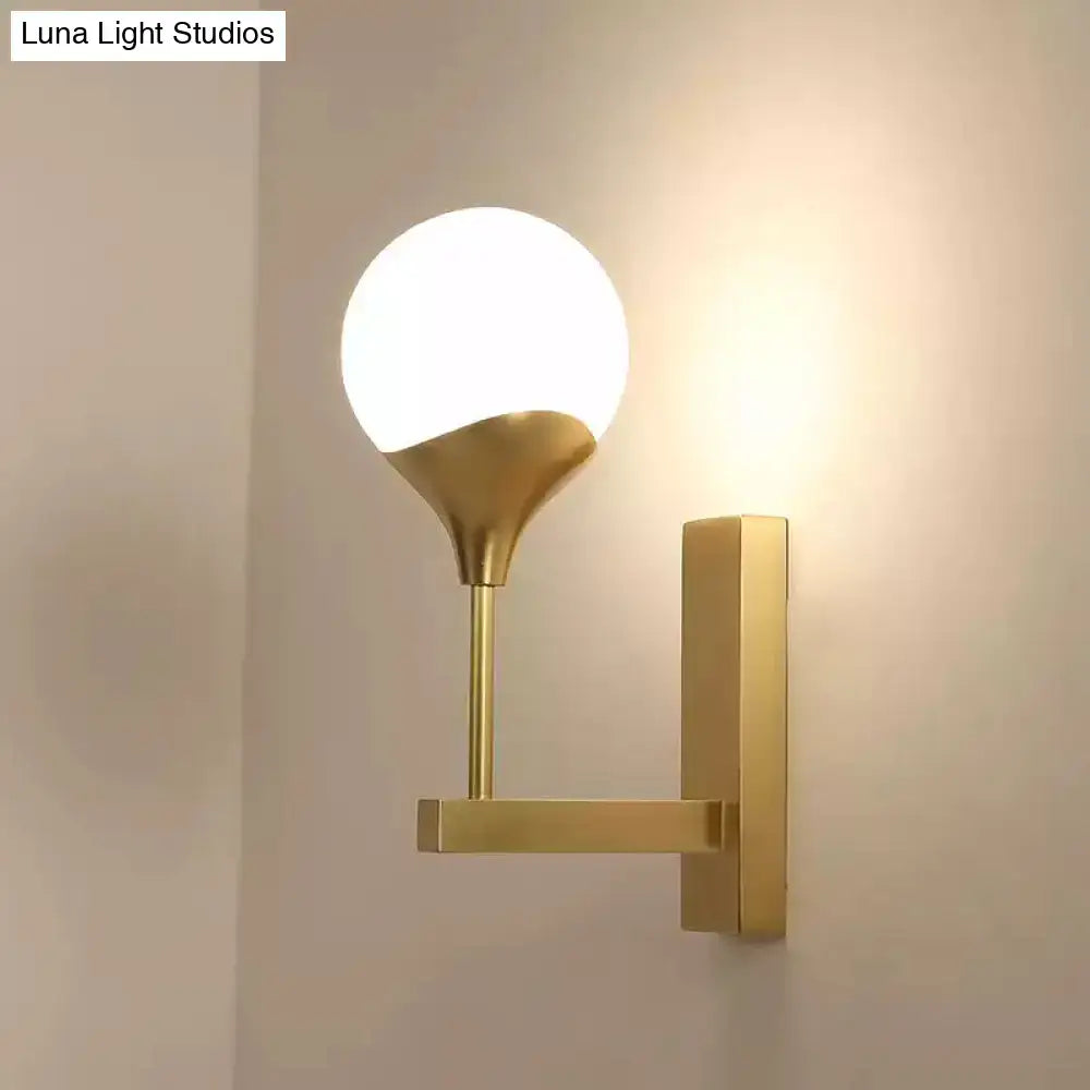 Modern brass wall lamp with cream glass shade – bedroom