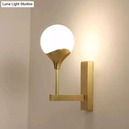 Modern brass wall lamp with cream glass shade – bedroom