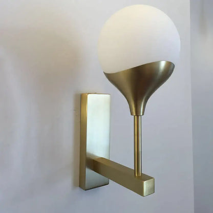 Modern brass wall lamp with cream glass shade – bedroom