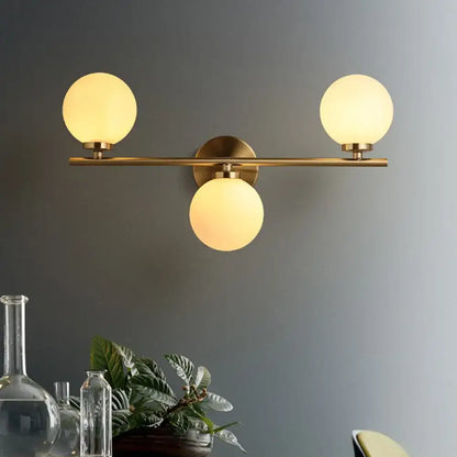 Modern gold 3-light wall sconce with white glass shades for bedroom