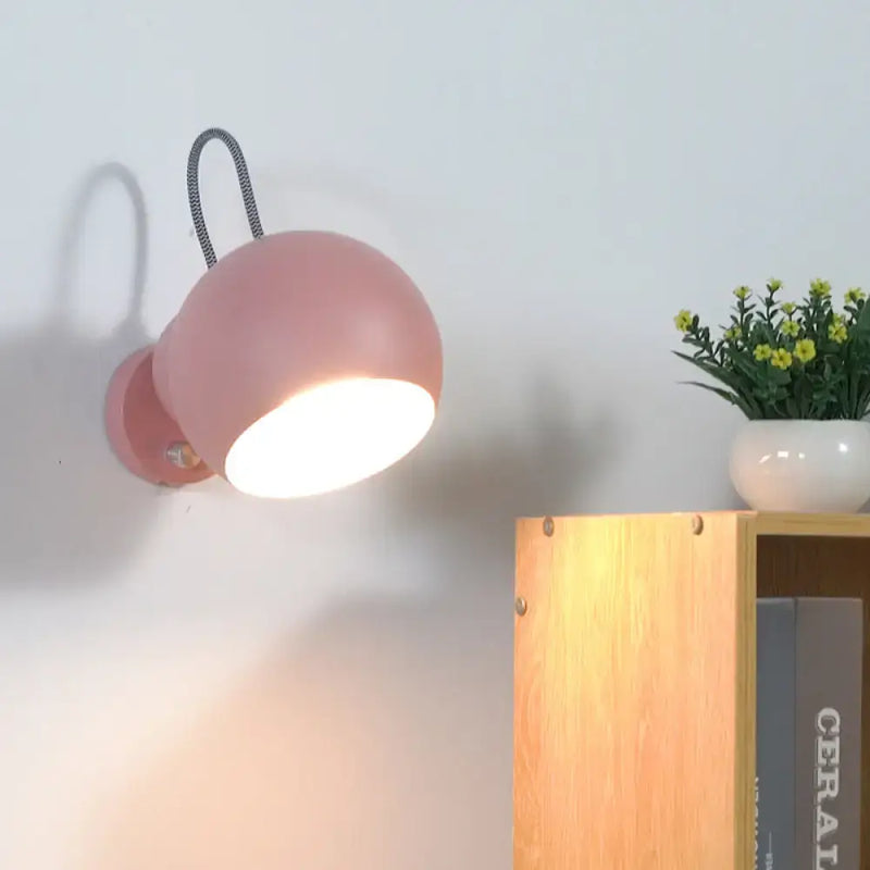 Modern pink spherical wall lamp with flexible black cord living room