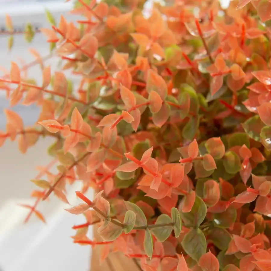 Orange & red artificial eucalyptus leaves in white pitcher – garden decor