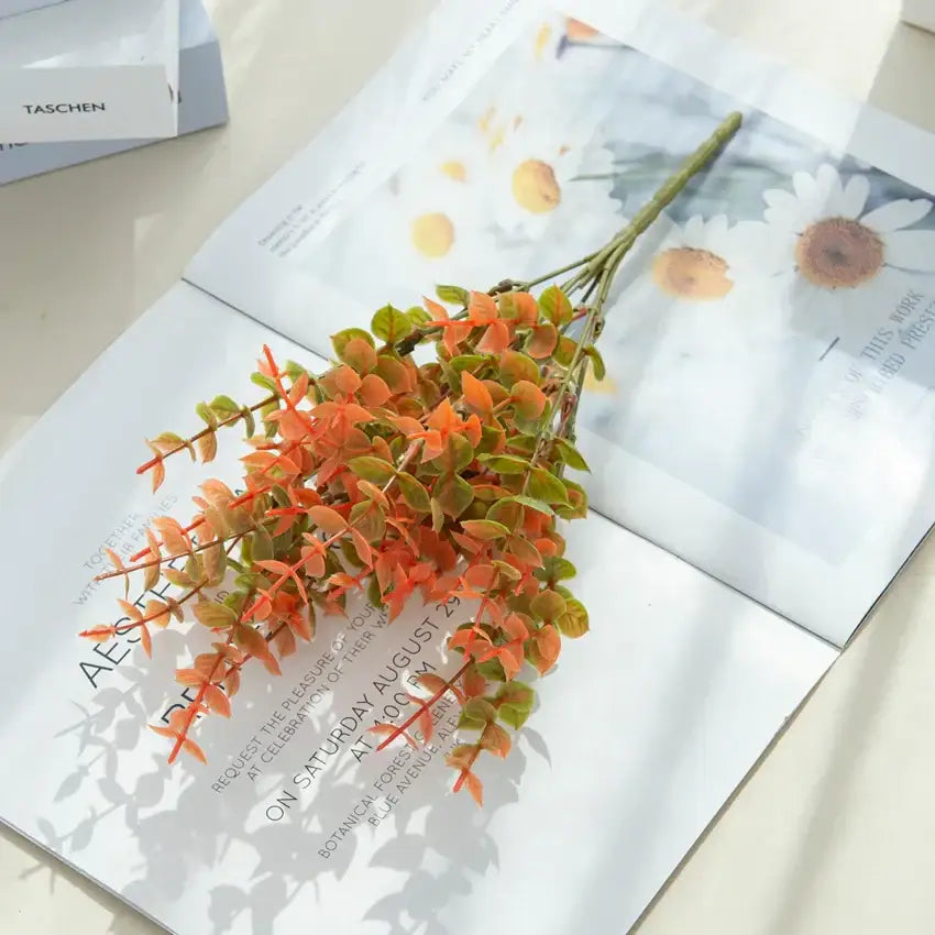 Orange & red artificial eucalyptus leaves in white pitcher – garden decor