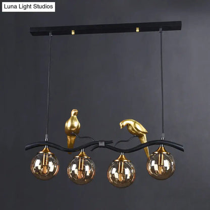 Postmodern black & gold bird pendant light with amber ball glass shade